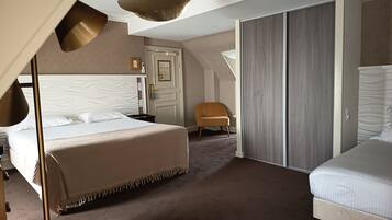 Een moderne hotelkamer met een groot bed, een kleiner bed, een kledingkast, een stoel en een plafondlamp.