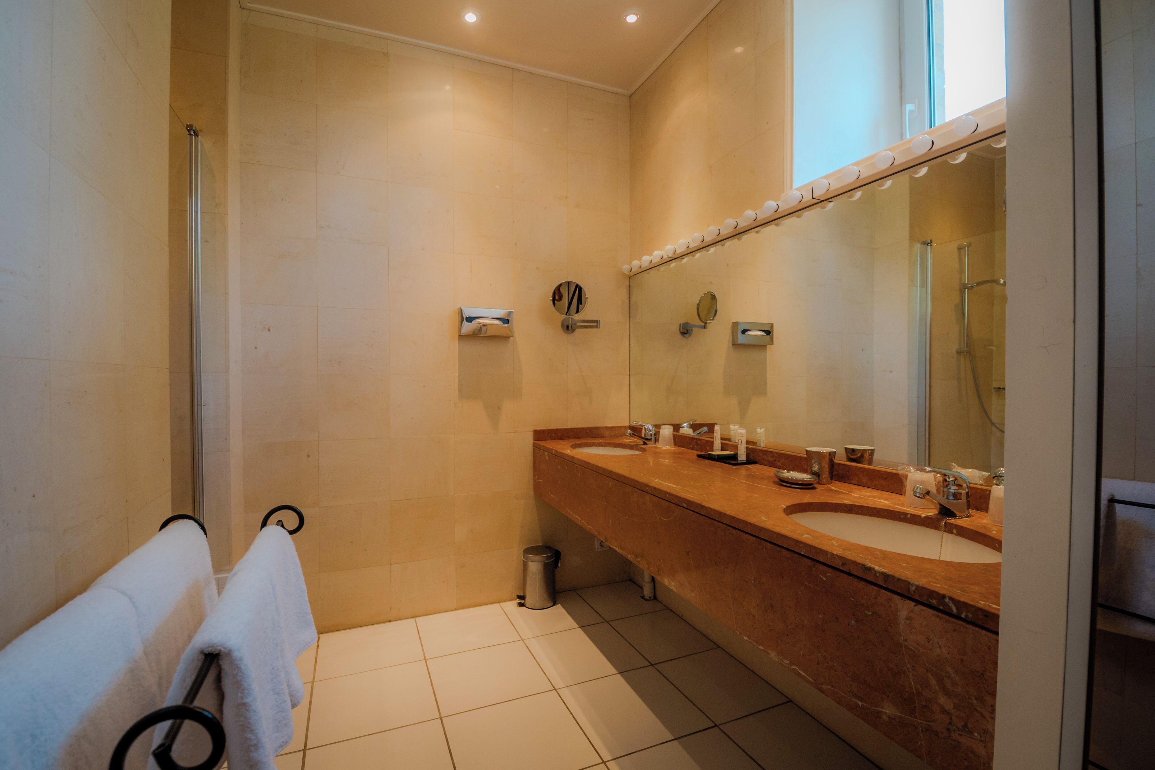 A modern bathroom with two sinks, a large mirror, and a towel rack.