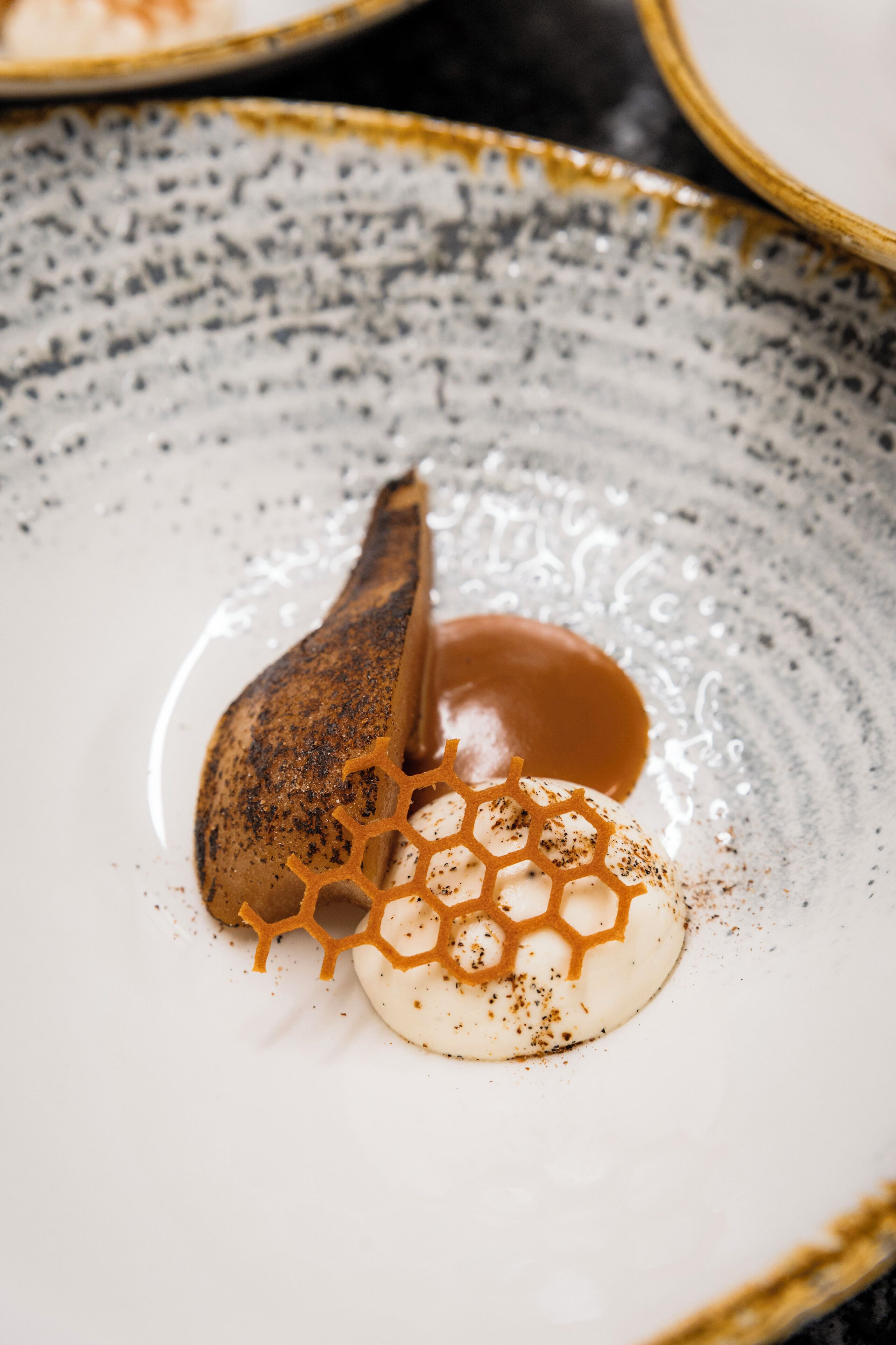 Un postre en un plato de cerámica con diseño de panal y un hilo de caramelo.