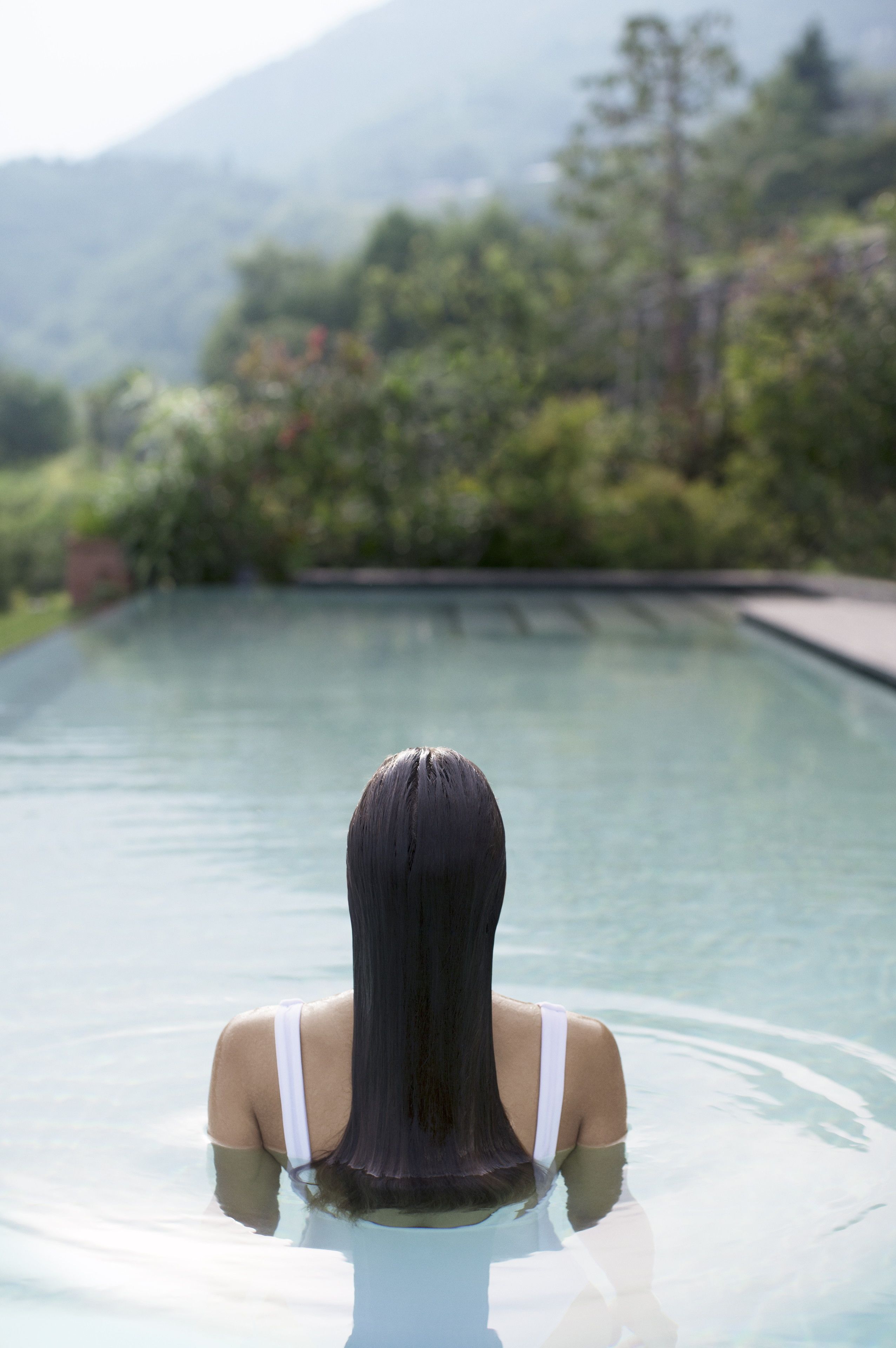Una persona en una piscina con un paisaje montañoso al fondo.