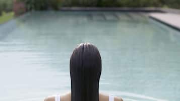 Una persona en una piscina con un paisaje montañoso al fondo.