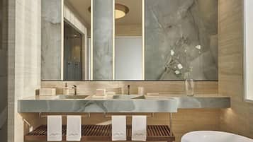 Un baño moderno con un espejo grande, dos lavamanos, una bañera y estantes de madera.