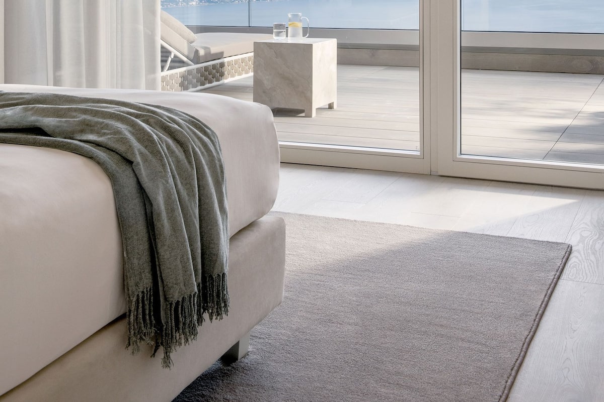 A bedroom with a large sliding glass door leading to a balcony with a city view.
