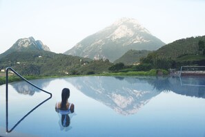 En person i en swimmingpool med utsikt över ett berg.