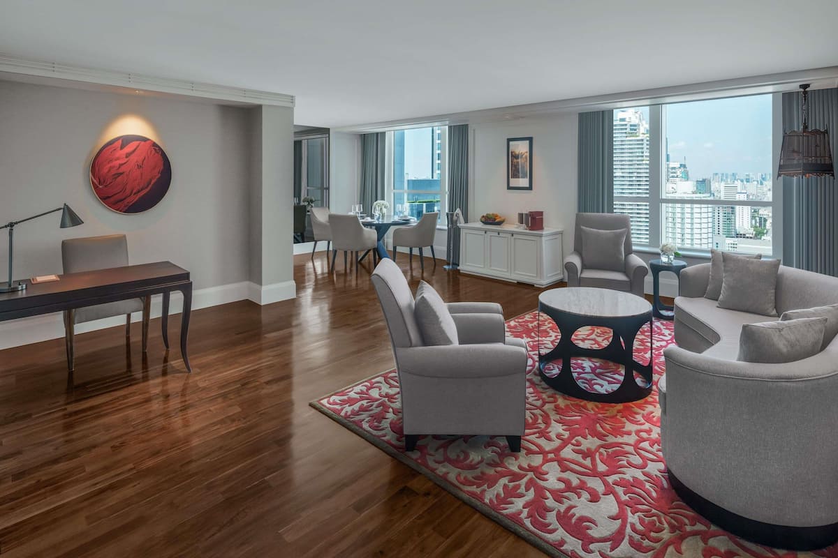 A modern living room with a dining area, a large window with a city view, and a red abstract painting on the wall.