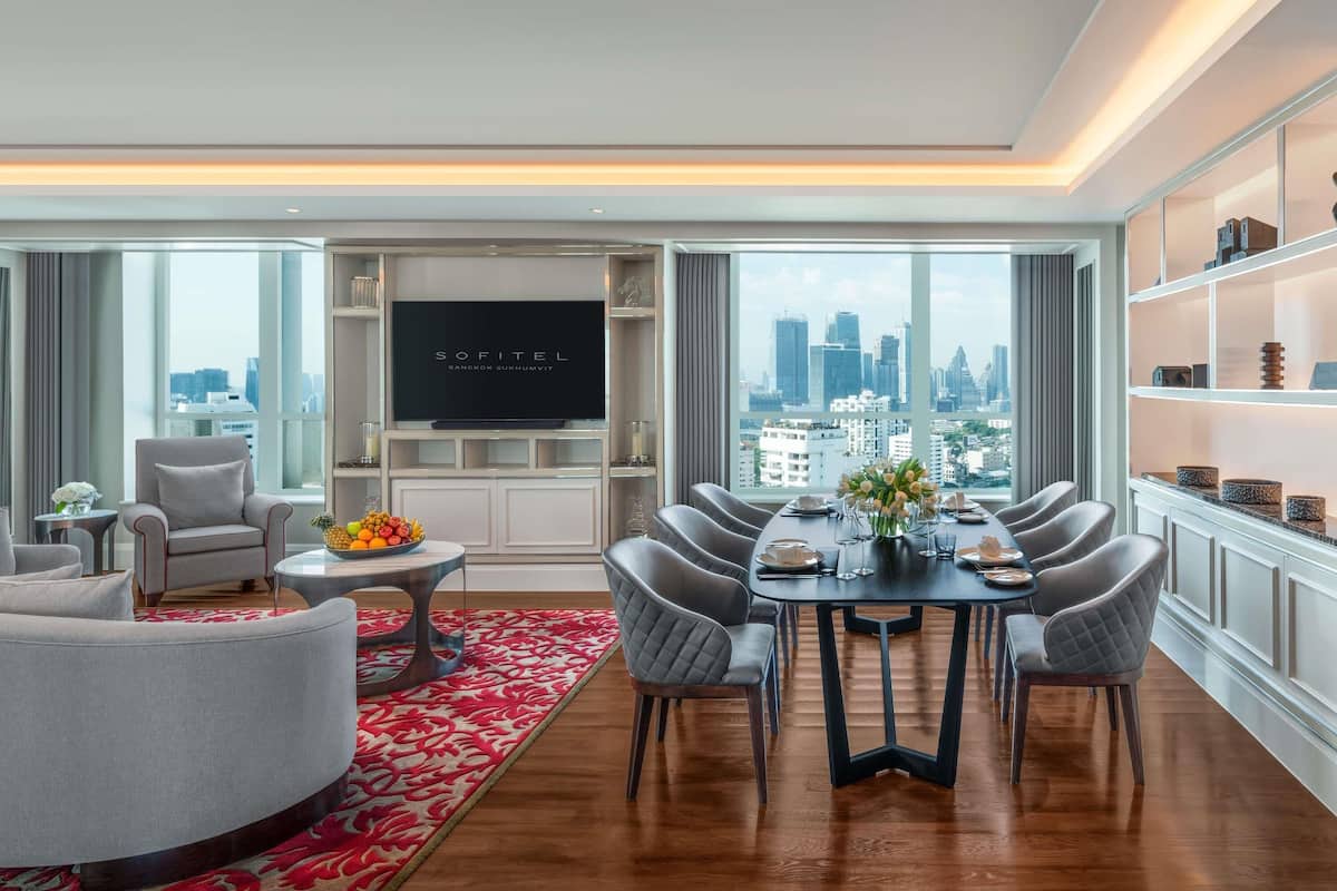 A modern living room with a dining area, a flat-screen TV, and a city view.