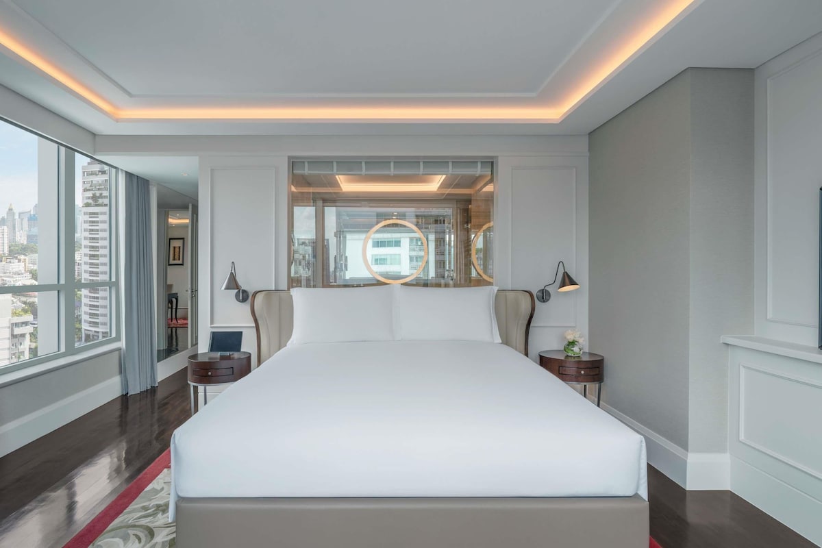 Habitación de hotel con una cama grande, vistas de la ciudad e iluminación moderna.