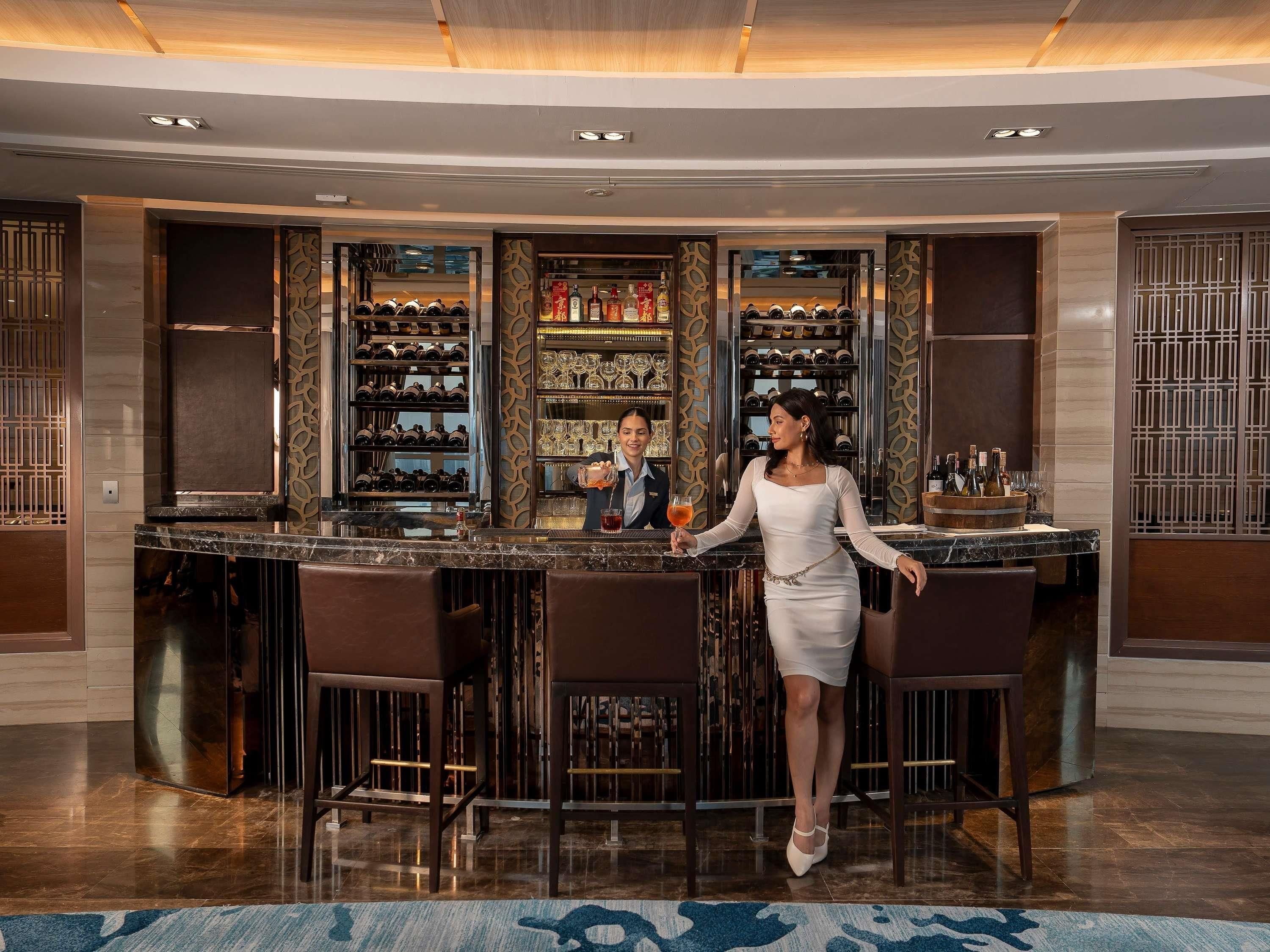 A bar area with a bartender, a wine rack, and a bar counter.