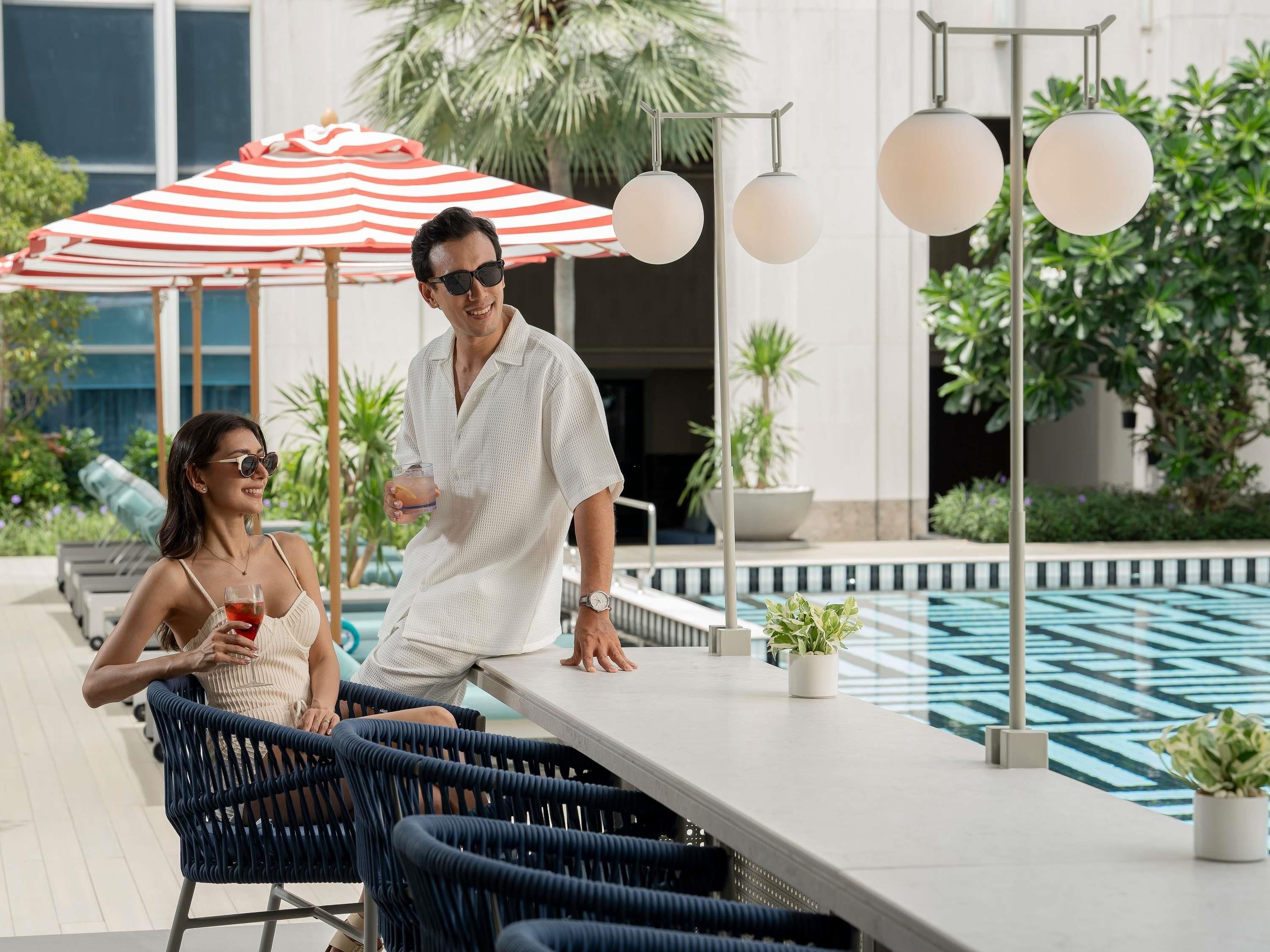 A poolside area with lounge chairs, a bar, and a red and white striped umbrella.