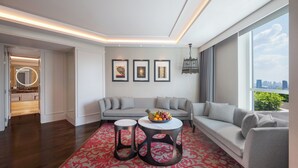 A modern living room with a grey sofa set, a coffee table with fruit, and a city view through large windows. - Sofitel Bangkok Sukhumvit (Bangkok)