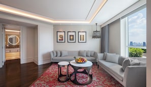 A modern living room with a grey sofa set, a coffee table with fruit, and a city view through large windows. - Sofitel Bangkok Sukhumvit (Bangkok)