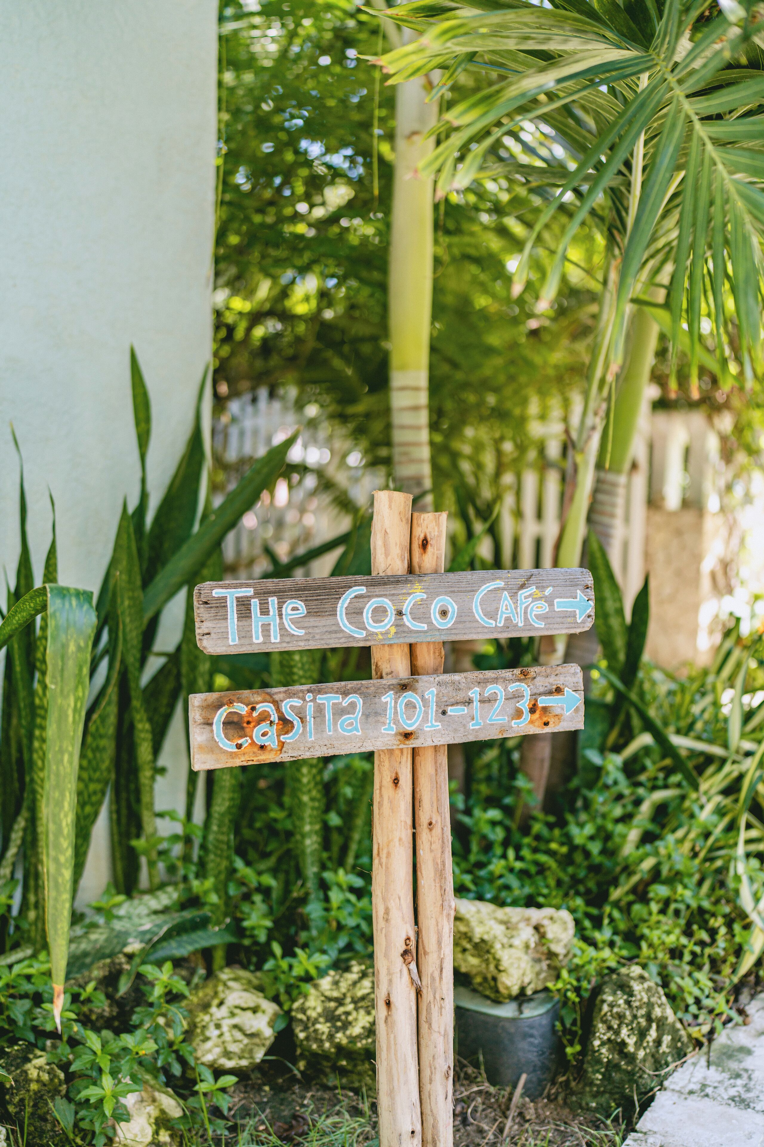 A wooden signpost with directions to 'The Coco Cafe' and 'Casita 101-123'.