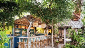 An outdoor bar area with wooden furniture and a thatched roof. - Boardwalk Boutique Hotel Aruba - Adults Only (Noord)