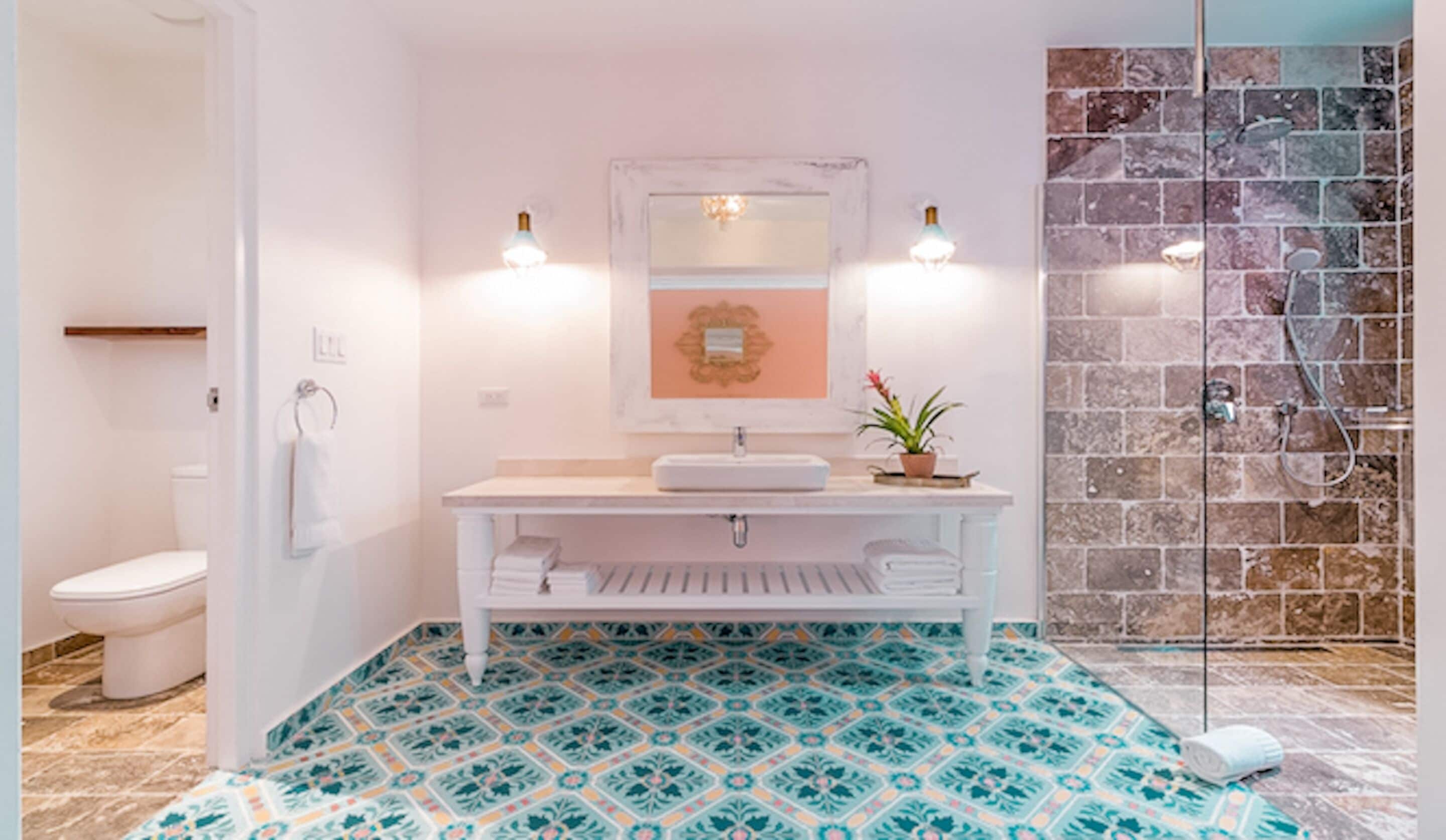 Un bagno con lavandino bianco, uno specchio e una doccia con parete in pietra.
