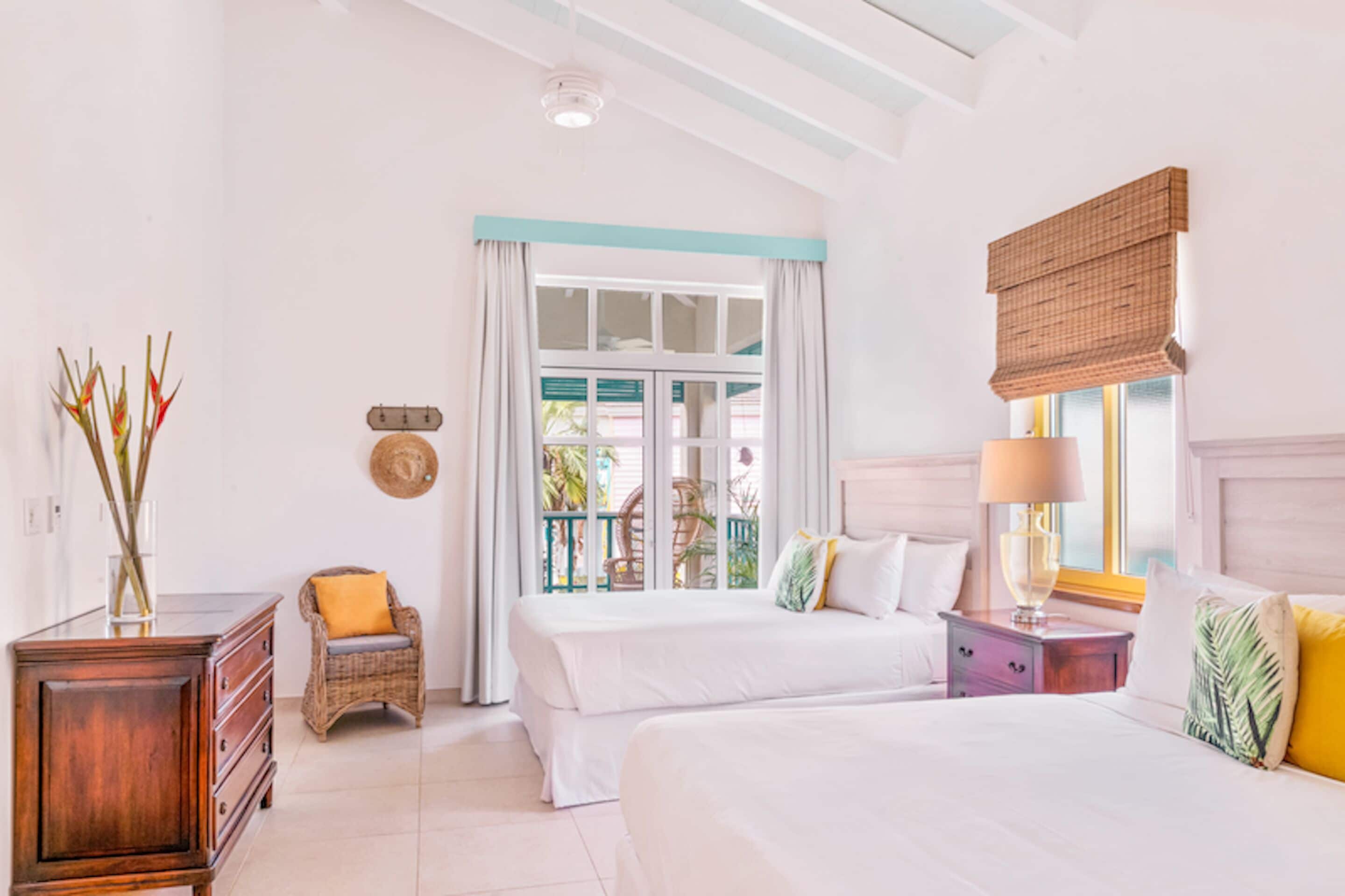 A bedroom with two beds, a dresser, a chair, and a window with curtains.