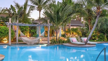 Relax by the serene pool surrounded by lush tropical vegetation and a hammock.