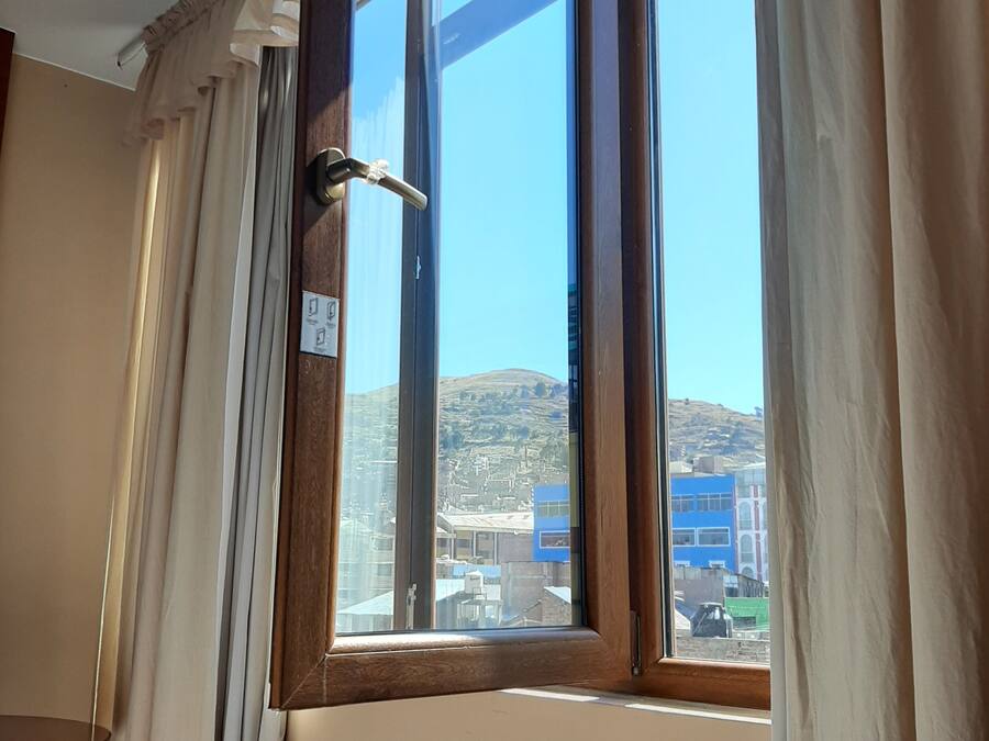 A room with a large window, curtains, and a wooden door.