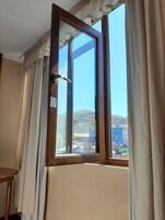 Una habitación con un ventanal grande, cortinas y una puerta de madera.