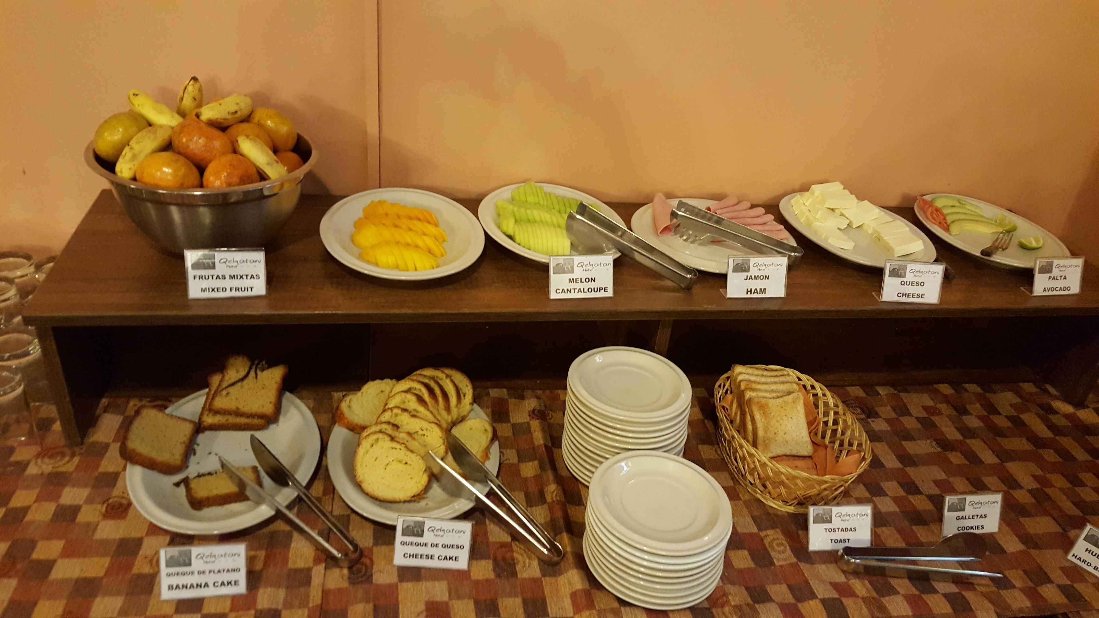 A buffet with various food items including fruits, cheese, ham, and bread.