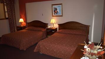 Habitación de hotel con dos camas, una mesita de noche con lámparas, un cuadro en la pared y una mesa con un florero.