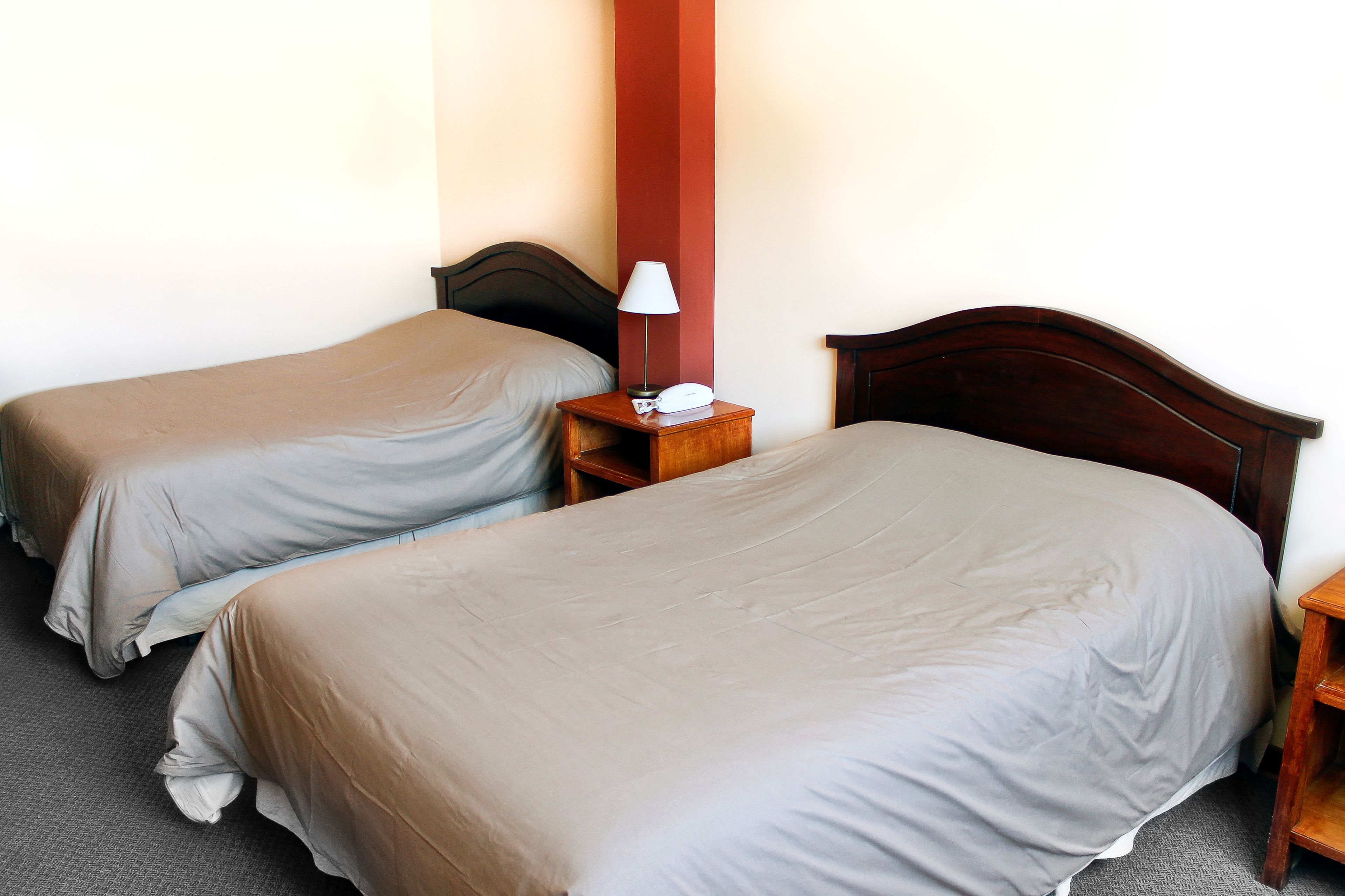 A hotel room with two single beds, a bedside table with a lamp, and a telephone.