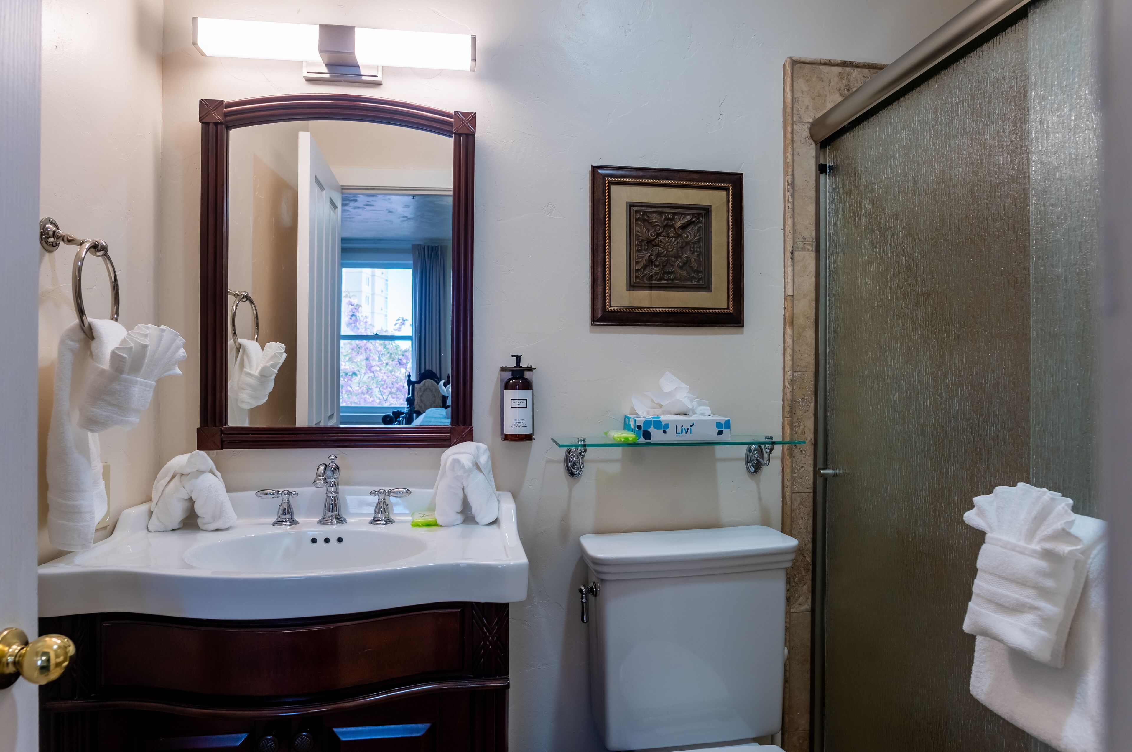 Un baño con lavamanos, espejo, inodoro y ducha.