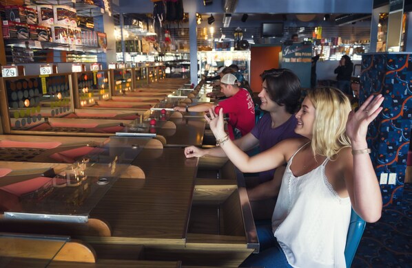 A bowling alley with multiple lanes, wooden tables, and seating areas.