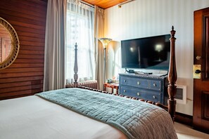 A hotel room with a large bed, a television, a dresser, and a lamp.