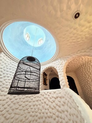 A room with a textured white ceiling, a skylight, and a hanging birdcage.