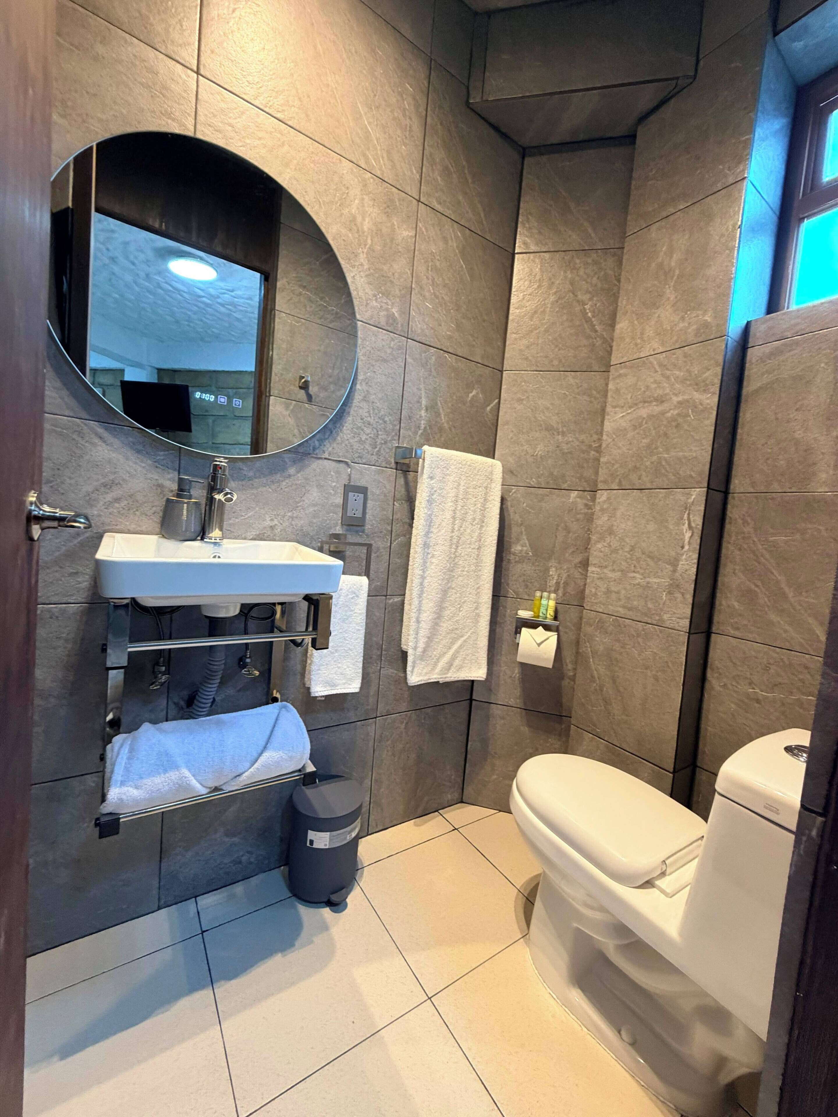 A modern bathroom with a sink, mirror, towel rack, and toilet.