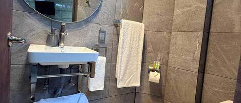 A modern bathroom with a sink, mirror, towel rack, and toilet.