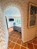 Una habitación con un techo de textura única, una cama con ropa de cama a rayas, un televisor en la pared y una obra de arte enmarcada.