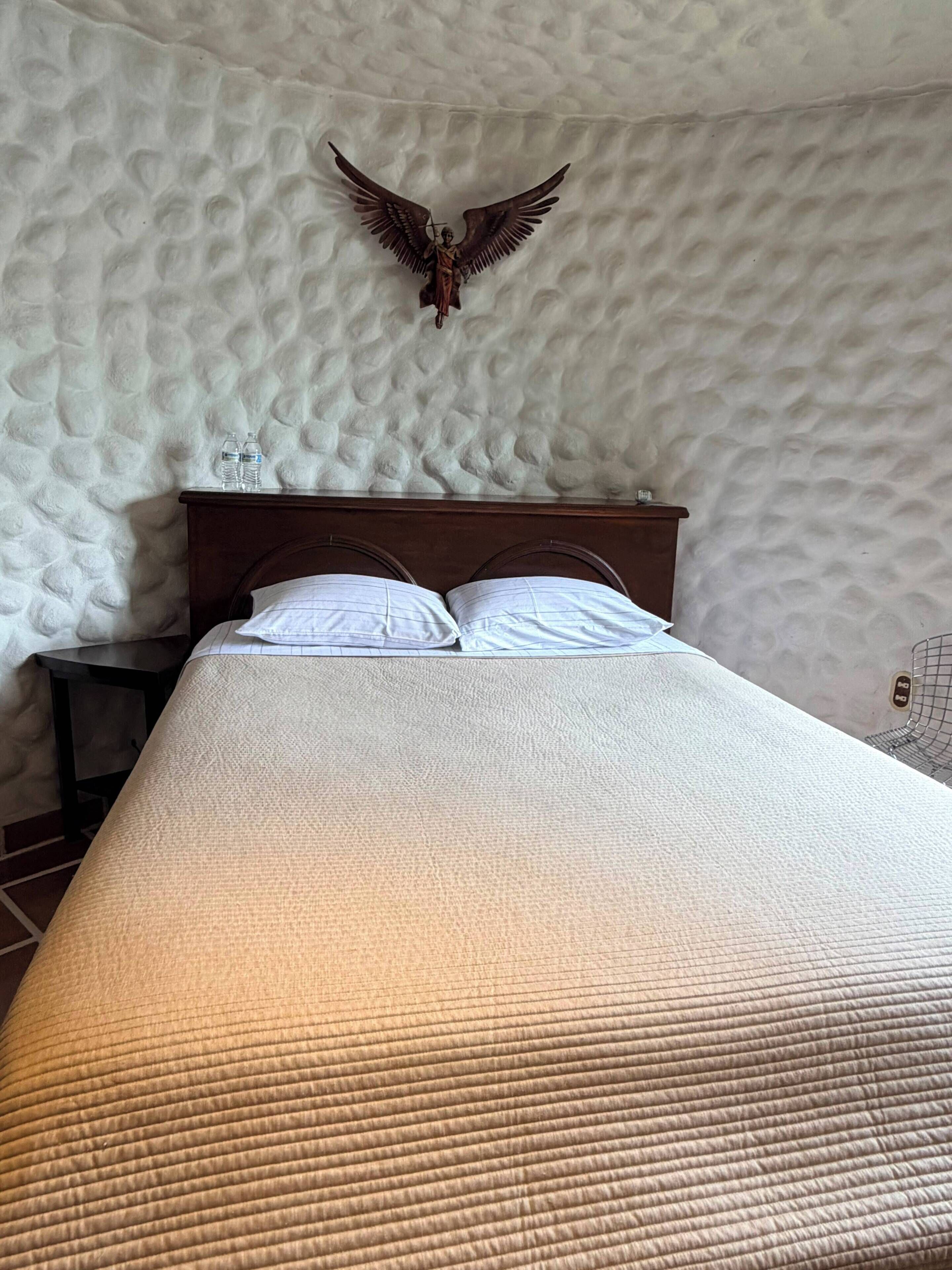 Una cama con pared texturizada y cabecera de madera.