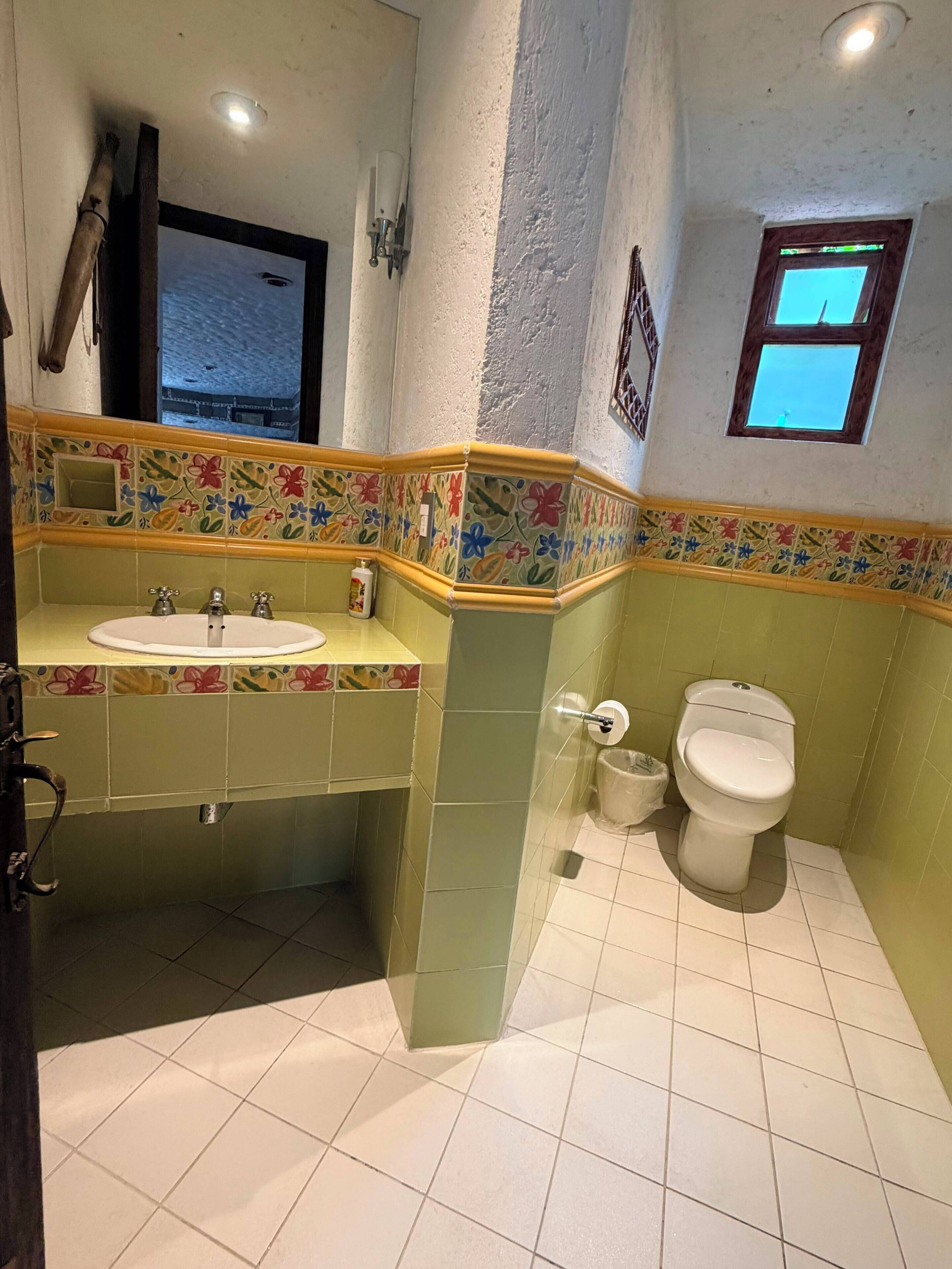 Un baño con lavamanos, inodoro y ventana.