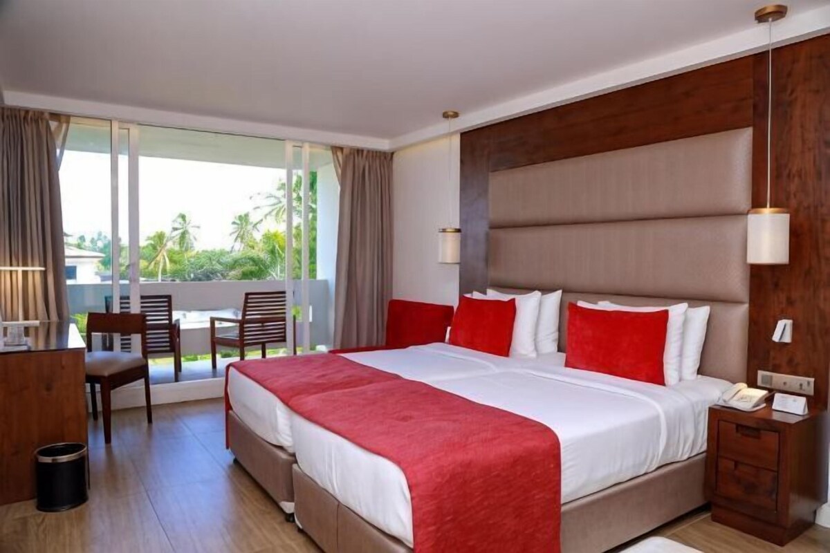 Une chambre d’hôtel avec un grand lit, un bureau, une chaise et une vue sur l’extérieur.