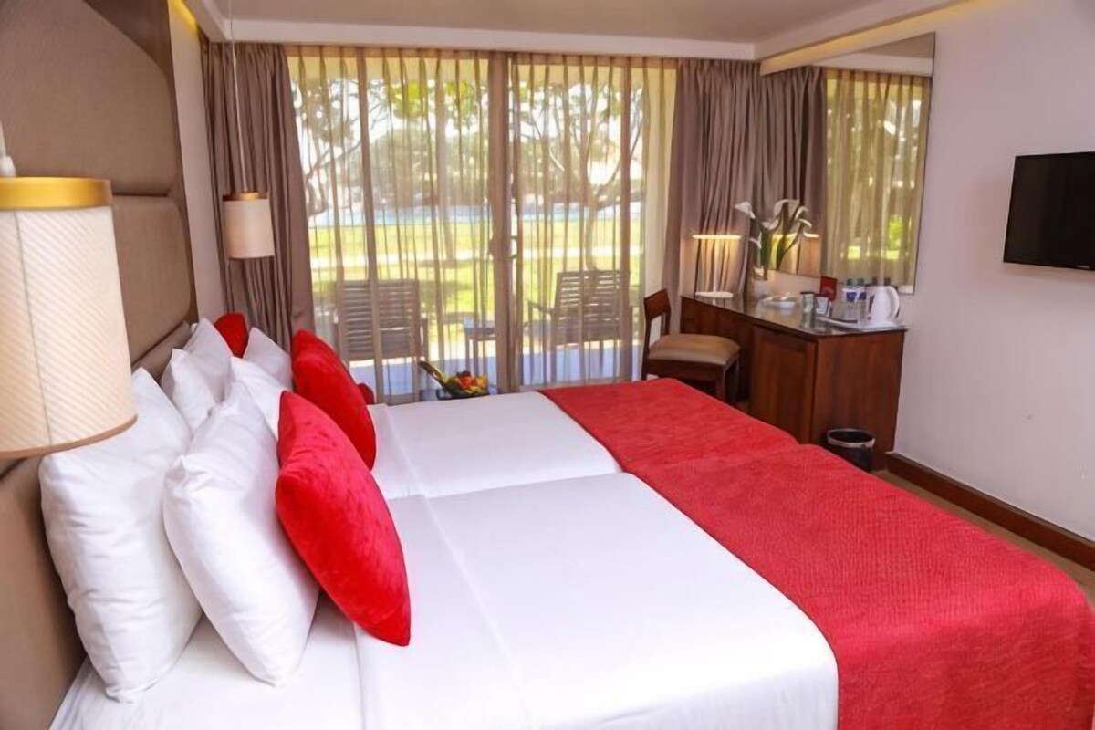 Une chambre d’hôtel avec un grand lit, un bureau, une chaise et une vue sur l’extérieur.