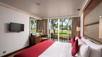 A hotel room with a large bed, a desk, a television, and a view of the outdoors.