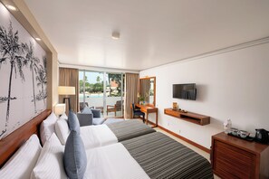 A hotel room with a bed, a desk, a TV, and a view of the outdoors. - Pegasus Reef - A Beach Resort in Colombo (Wattala)