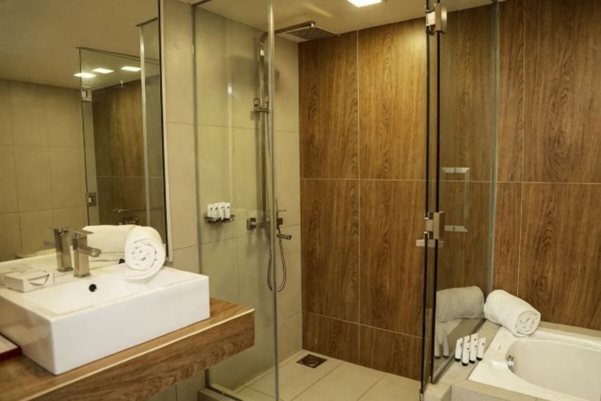 Une salle de bain moderne avec une douche à parois de verre, un lavabo blanc et un meuble-lavabo en bois.