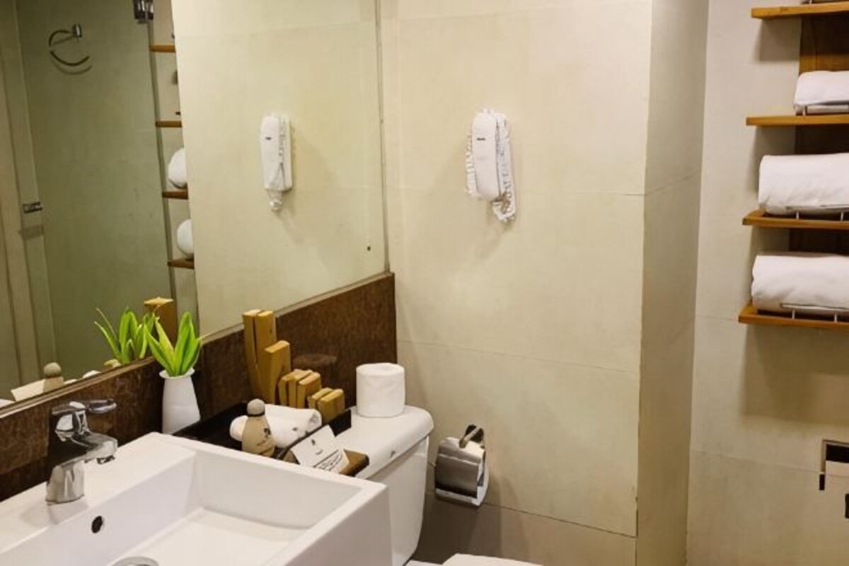 Une salle de bain équipée d’un lavabo, d’un miroir, d’un porte-serviettes et de toilettes.