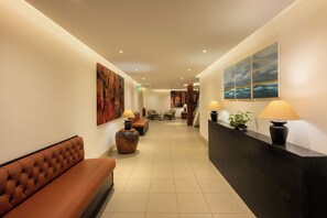 A hotel lobby with a reception desk, seating area, and artwork on the walls.