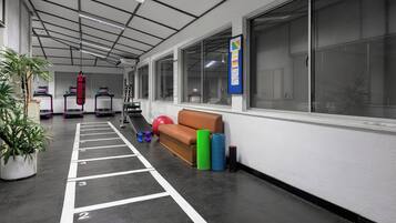 Ein Fitnessraum mit Trainingsgeräten, einer Startlinie für eine Laufbahn und einem großen Fenster.