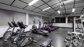 Ein Fitnessstudio mit Laufbändern, Crosstrainern und Gewichten.
