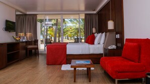 Una habitación de hotel con una cama, un sofá rojo, una mesita, un escritorio y un televisor.
