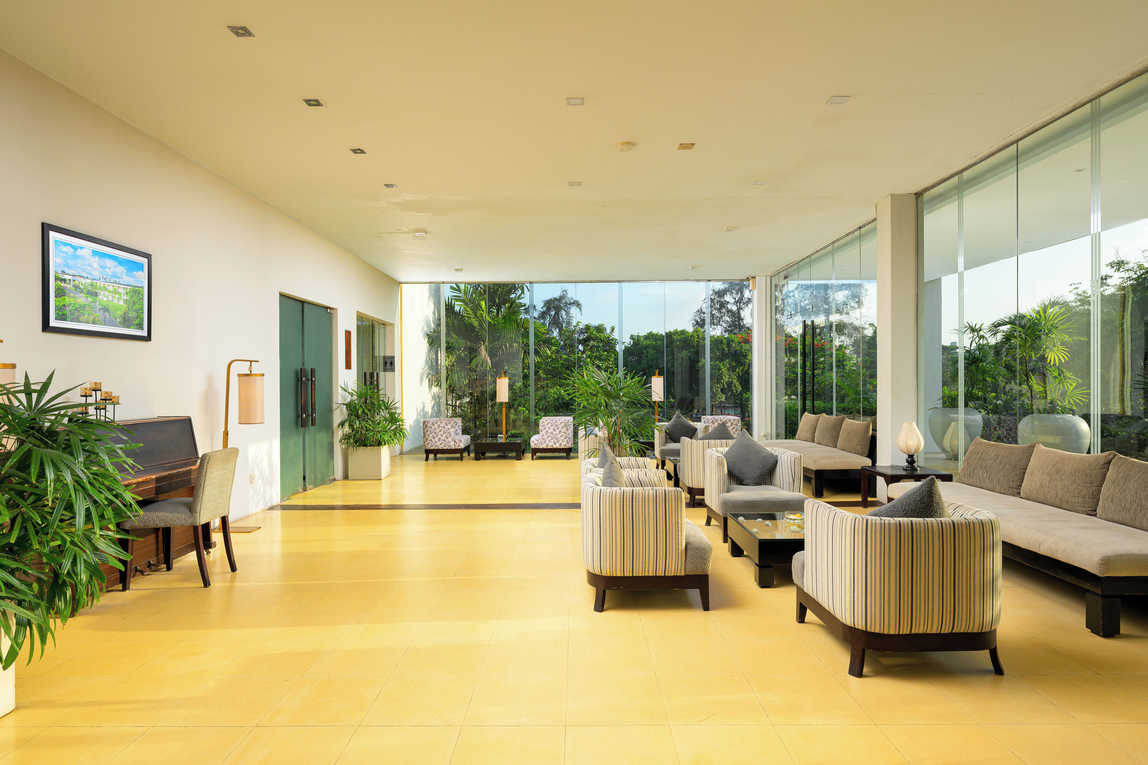 A spacious lobby with a piano, seating area, and large windows offering a view of greenery.