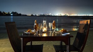 Mesa para dos en la playa, con el horizonte urbano al fondo.