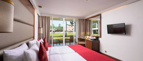 Quarto de hotel com cama, escrivaninha, televisão e vista para o exterior.