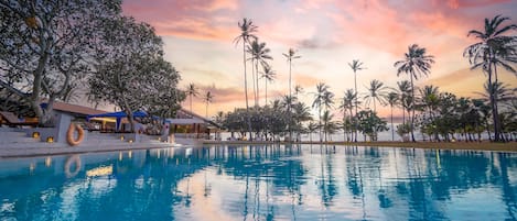Una piscina al aire libre, sombrillas, sillones reclinables de piscina