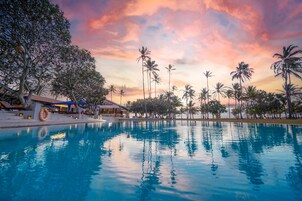 Una piscina al aire libre, sombrillas, sillones reclinables de piscina