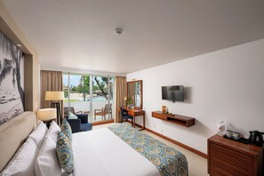 A hotel room with a bed, a desk, a TV, and a view of the outdoors.